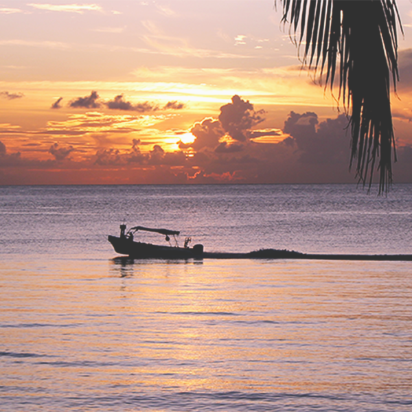 A boat driving by during a sunset in Cozumel