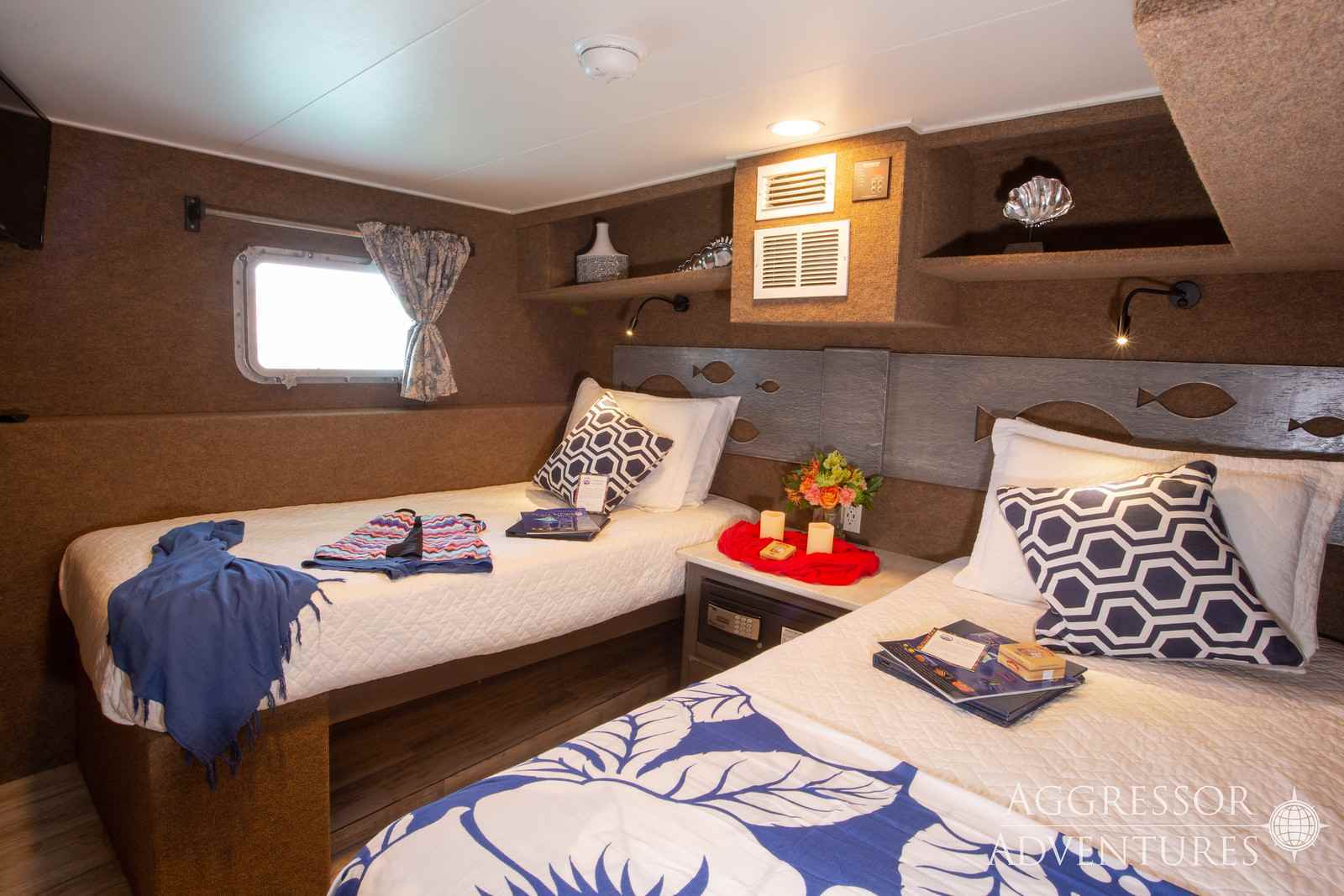 In a cabin of the Cayman Aggressor, there are two twin beds nicely prepared with sheets, extra pillows, blankets, and a treat.